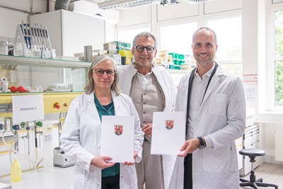 Nach Unterzeichnung der Vereinbarung machten sich Prof. Dr. Antje Krause (links), Oberbürgermeister Thomas Feser (Mitte) und Wissenschaftsminister Clemens Hoch (rechts) im Labor ein Bild von aktuellen Forschungsprojekten.