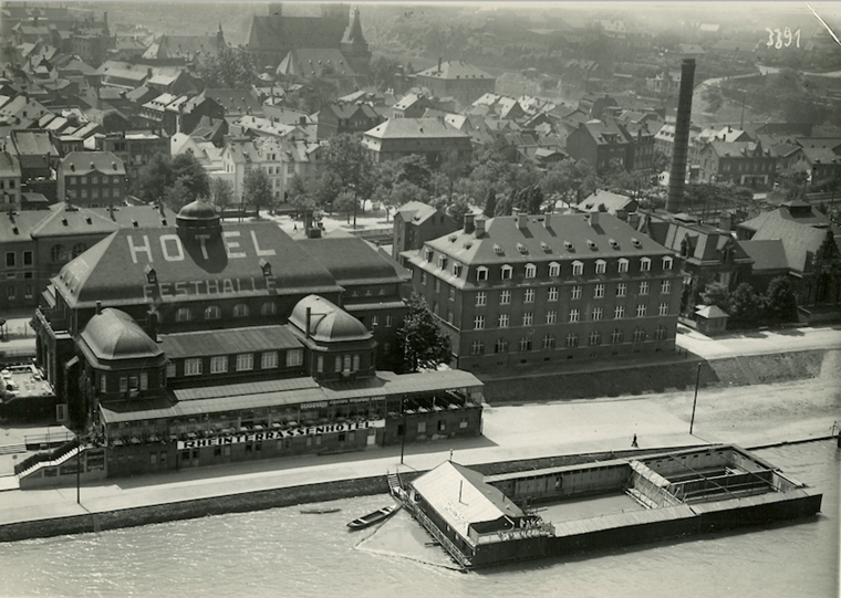 Die Badeanstalt 1928. Dahinter Festhalle (heute Palazzo/Palais), daneben die Marne-Kaserne (heute „Hildegarten“ sowie Parkfläche), rechts außen das Binger Elektrizitätswerk (heute Museum am Strom – Hildegard von Bingen.