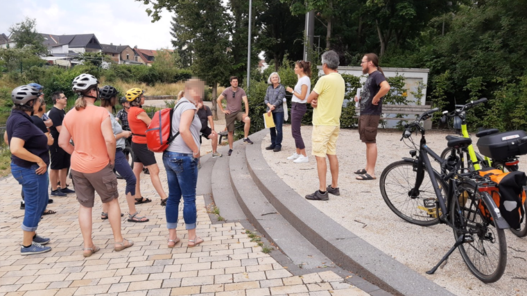 Zwischenstopp bei der Fahrradtour zu Energie- und Klimaschutzprojekten – Klimaschutzmanagerin Lisa Christmann (3.v.r.) erläutert die Details der jeweiligen Stationen