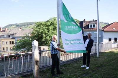 Oberbürgermeister Thomas Feser (r.) und Peter Heyn hissen die Flagge für den Frieden.